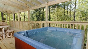 Ein Whirlpool auf einer Holzterrasse mit Holzzaun und Picknicktischen.