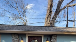 A house with a wooden front door, stone accents, and two metal chairs on a concrete porch. - The Moon and the Stars Cottage- in Town! (Nashville)