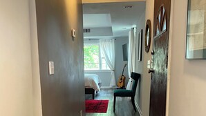 A hallway with a wooden floor, a red rug, a green chair, and a guitar leaning against the wall. - The Moon and the Stars Cottage- in Town! (Nashville)