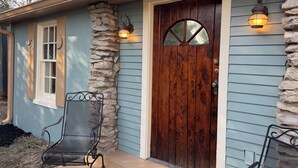 A house with a wooden front door, stone pillar, and two metal chairs on the porch. - The Moon and the Stars Cottage- in Town! (Nashville)