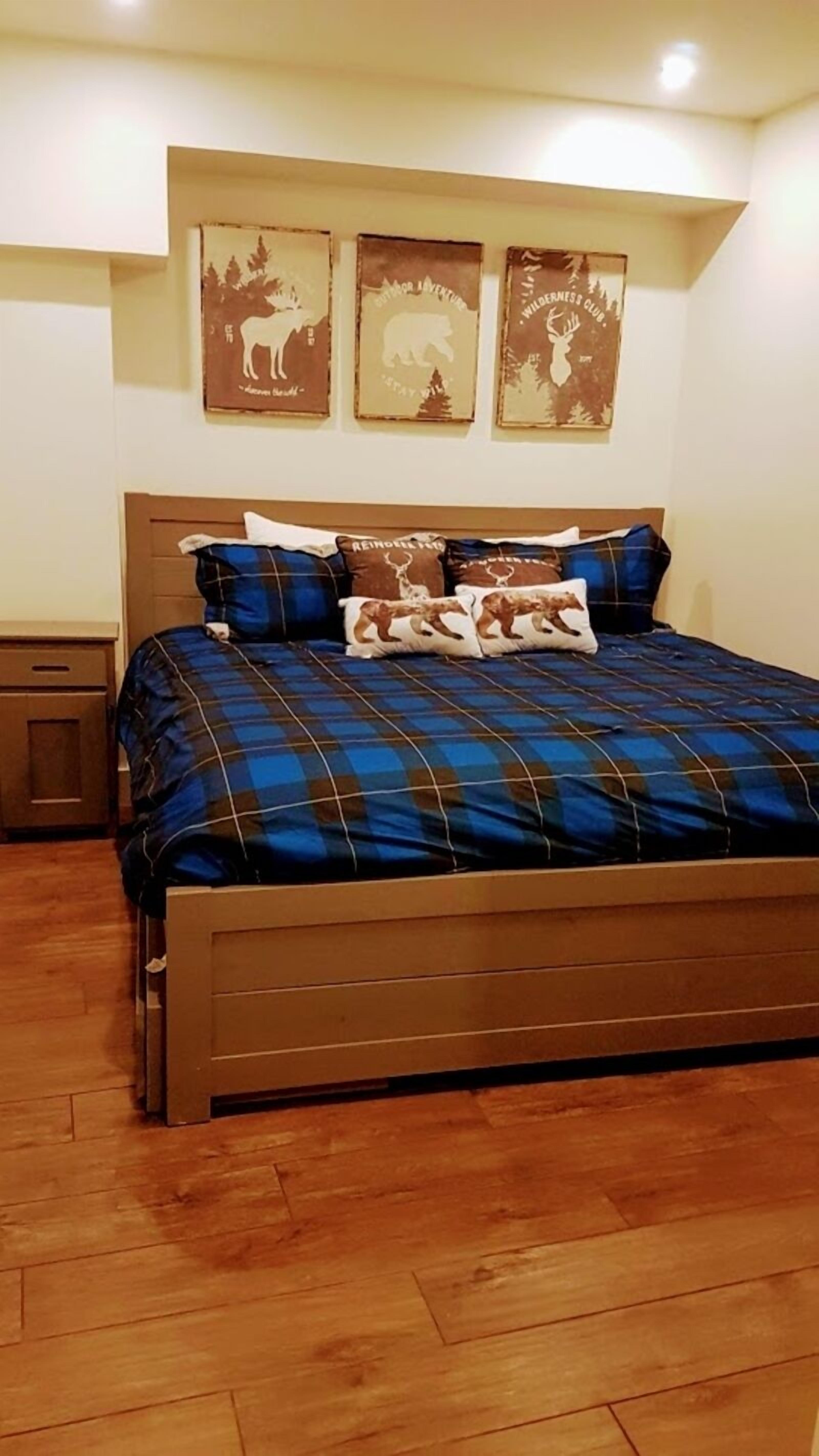 Une chambre avec un grand lit, une tête de lit en bois et trois affiches accrochées au mur.