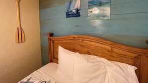 Un lit en bois avec un oreiller blanc et une cuillère en bois accrochée au mur.