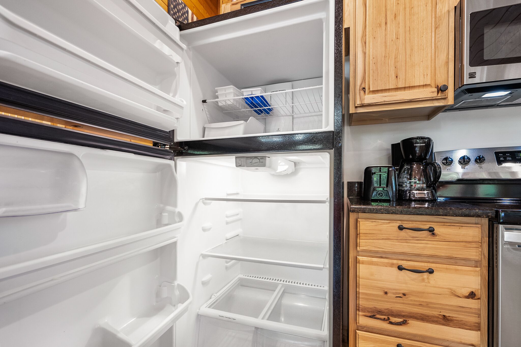 A kitchen with a built-in refrigerator, wooden cabinets, a coffee maker, and a microwave.