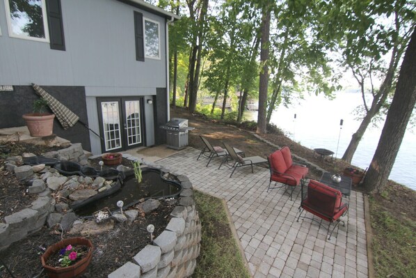 Eine Terrasse mit Grill, Sitzgelegenheiten im Freien und Blick auf einen See.