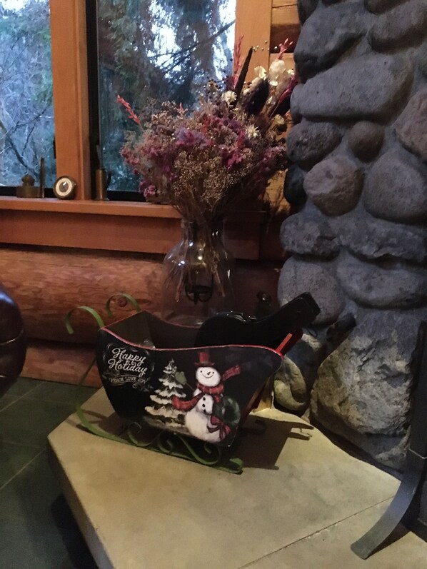 A table with a vase of flowers, a snowman-themed gift basket, and a stone wall.