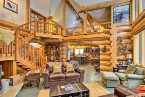 A log cabin interior with a wooden staircase, leather furniture, and a rustic decor.