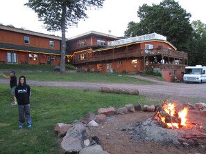 Un chalet avec une façade en bois, une terrasse et un foyer au premier plan.