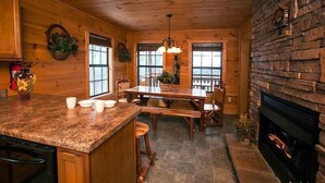 Un intérieur en bois avec un îlot de cuisine, une table à manger et une cheminée.