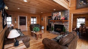 L’intérieur d’un chalet confortable, avec un foyer en pierre, des planchers en bois et un plafond haut.