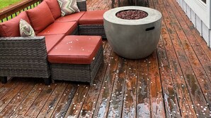 Une terrasse en bois aménagée avec du mobilier d’extérieur, notamment un canapé et des fauteuils, ainsi qu’un foyer.