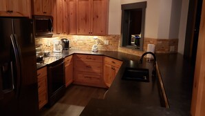 Una cucina moderna con mobili in legno, elettrodomestici in acciaio inox, una macchina per il caffè e un frullatore.