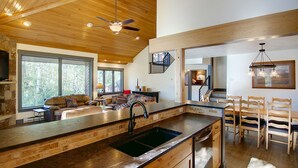 Un'ampia cucina con una grande isola, soffitto in legno e vista sull'esterno.