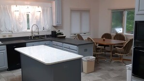 A modern kitchen with a central island, a dining area with a table and chairs, and a built-in oven. - Golf front home with 8 beds (Pinehurst)