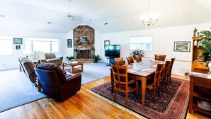 A spacious living room with a fireplace, a dining area with a large table and chairs, and a cozy seating area with sofas and a recliner. - Golf front home with 8 beds (Pinehurst)