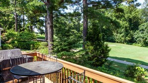 A deck with a table and chairs, overlooking a well-maintained lawn and trees. - Golf front home with 8 beds (Pinehurst)