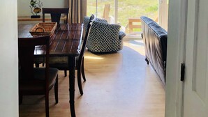 A dining area with a view of the ocean, a dining table with chairs, a wicker basket, and a patterned ottoman. - Oceanfront Duplex - Sleeps 10 - Great Price!! 3 B/R, 2.5 bath, outdoor shower (Atlantic Beach)
