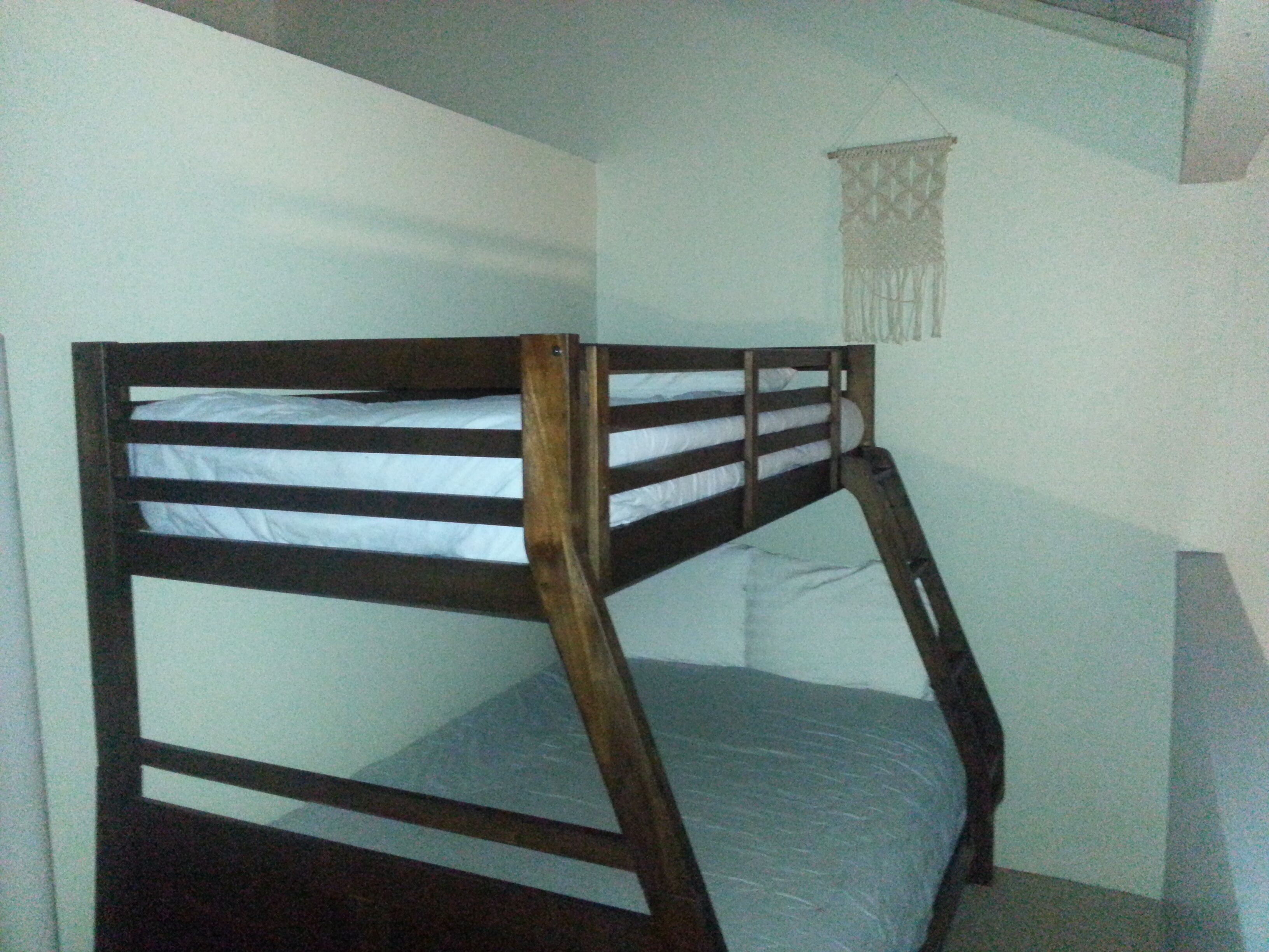 Un lit superposé avec une structure en bois et un matelas.