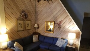 A cozy living room with a blue sectional sofa, a wooden coffee table, and two side tables with lamps. - Charming 2 Bedroom + Loft Condo Special Winter Ratesl (Mammoth Lakes)