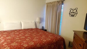 A hotel room with a large bed, a wooden dresser, a lamp, and a bear-themed wall decoration. - Charming 2 Bedroom + Loft Condo Special Winter Ratesl (Mammoth Lakes)