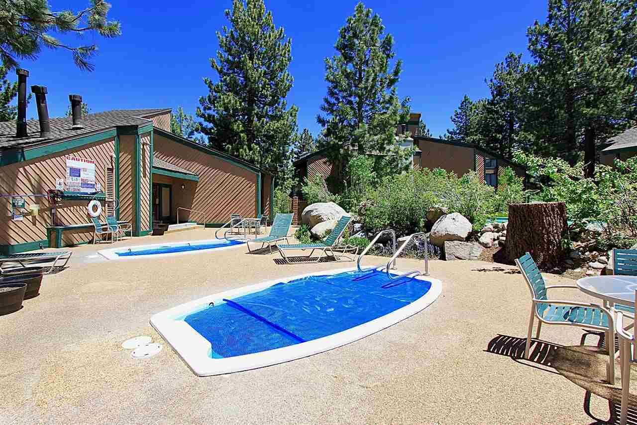 A pool area with lounge chairs and a small building with a sign.