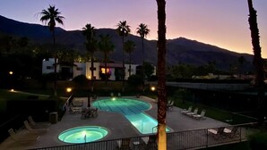 A pool area with lounge chairs and a building in the background. - Gorgeous condo with fabulous mountain and pool views in South Palm Springs (Palm Springs)