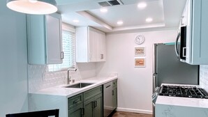 A modern kitchen with white cabinets, a dining table with chairs, and a built-in stove. - Gorgeous condo with fabulous mountain and pool views in South Palm Springs (Palm Springs)