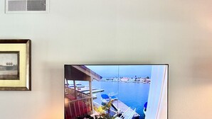 A television mounted on a wooden wall unit with a view of a harbor and boats. - Gorgeous condo with fabulous mountain and pool views in South Palm Springs (Palm Springs)