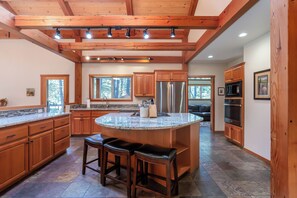 A spacious kitchen with wooden cabinets, a large island with stools, and a built-in oven.