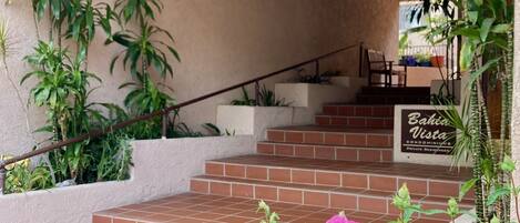Una escalera conduce a un balcón con plantas en macetas y un letrero que dice "Bahia Vista Condominium Private Residences".