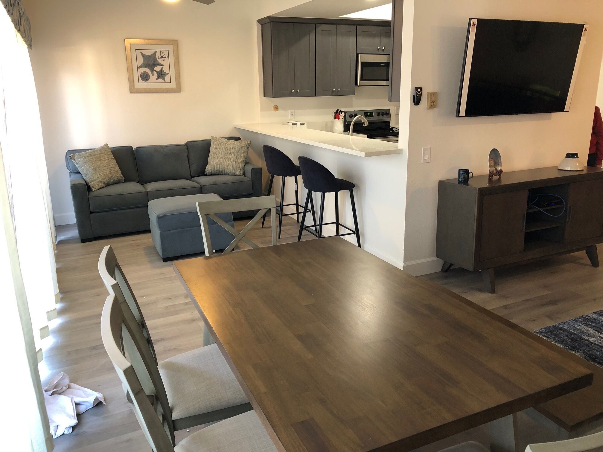 Een moderne woonruimte met een eethoek, keuken en een wandgemonteerde flatscreen-tv.