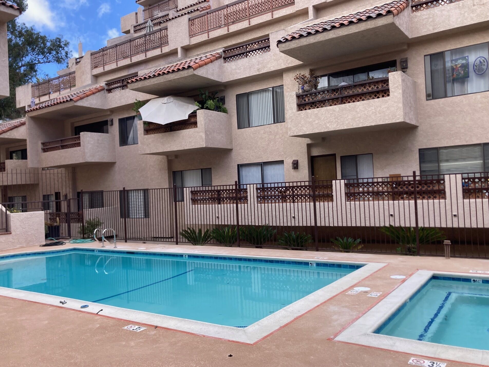 A multi-story residential building with a swimming pool in the foreground.