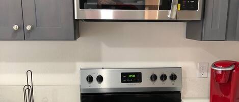 A kitchen with a stainless steel microwave, oven, and stovetop.