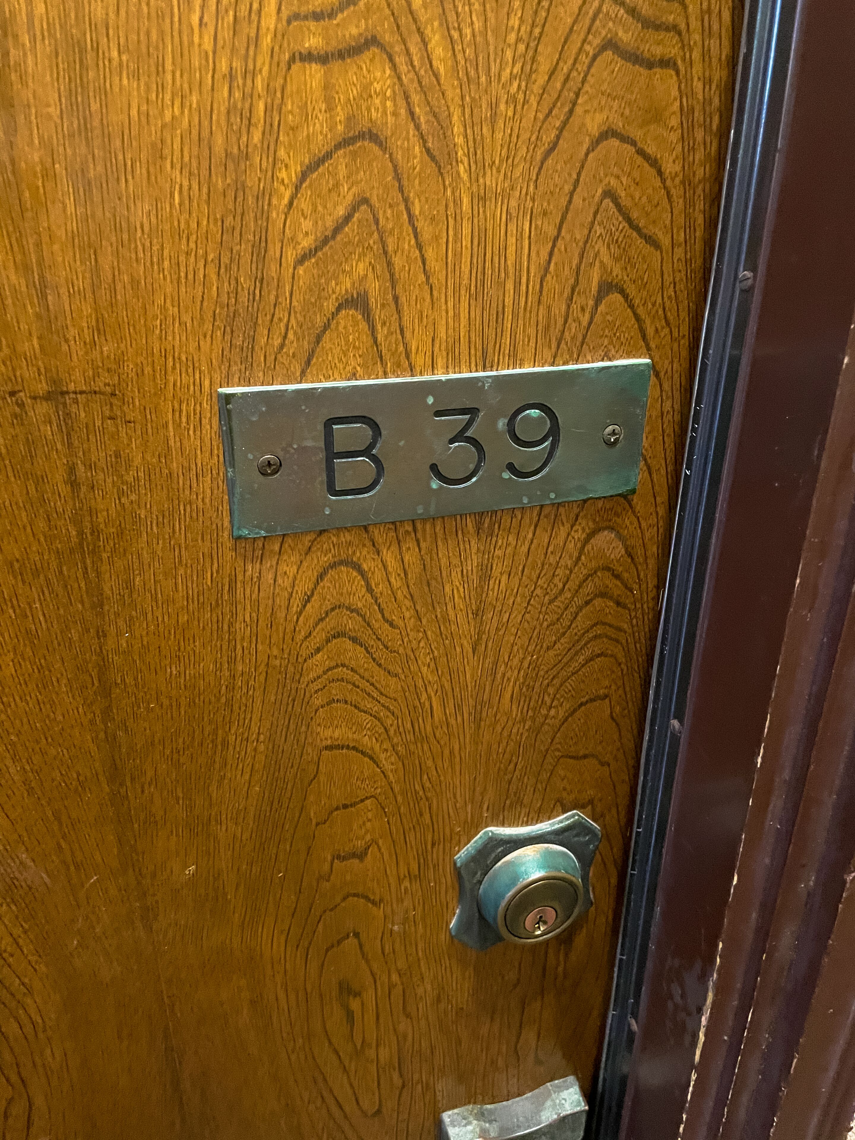 A wooden door with a metal plate labeled "B 39" and a keyhole below it.