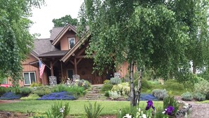 Un jardín bien cuidado con un estanque, diversas flores y una casa con porche.