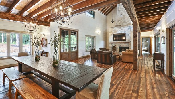 Amplia sala de estar con una gran mesa de madera, asientos cómodos, chimenea de piedra y pared de televisión de piedra.