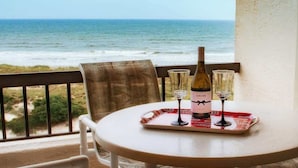 A table with a bottle of Chloe wine, two glasses, and a menu on a balcony overlooking the ocean. - Surf & Racquet Club C126 - Pool! (Amelia Island)