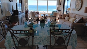 Enjoy dining and relaxation in this inviting space with a round table for four, comfortable sofa, and ocean views.