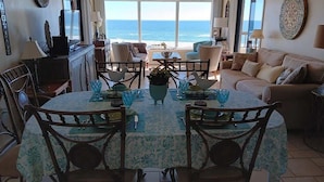 A dining area with a round table, chairs, and a view of the ocean. - Surf & Racquet Club C126 - Pool! (Amelia Island)