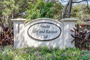 Enter the Amelia Surf and Racquet Club, surrounded by lush greenery.