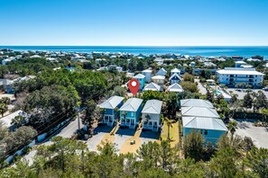 A coastal residential area with houses, a clear blue sky, and the ocean in the background. - Nestled near beach-new updates-community pool-near shops, restaurants & cafes. (Santa Rosa Beach)