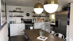 A modern kitchen with white cabinetry, a wooden dining table, and stainless steel appliances.