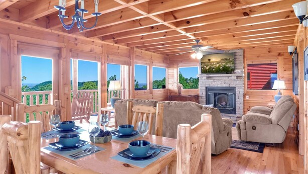 A wooden cabin interior with a dining area, seating, and a fireplace.