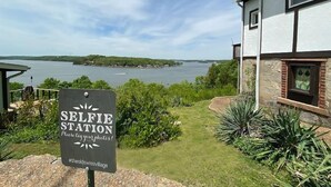 Señal de estación de selfies con vista a un lago y una casa al fondo.