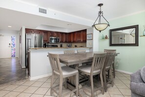 A modern kitchen with a central island, wooden chairs, and a dining table. - Stay @ Tide of 5 on Folly Beach (Folly Beach)