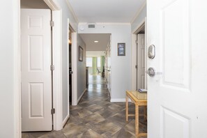 A hallway with white doors, a wooden table with a scale, and a view into a room with a green wall. - Stay @ Tide of 5 on Folly Beach (Folly Beach)