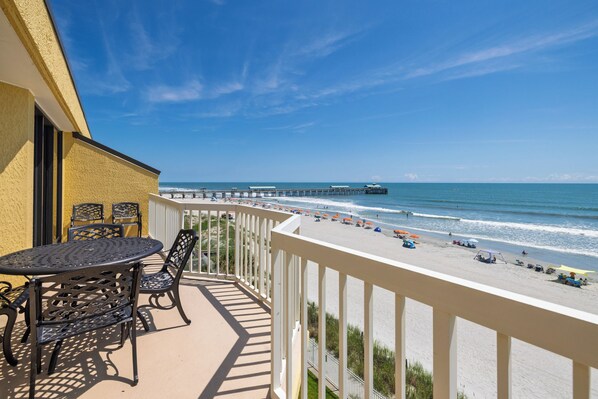 A balcony with a view of a beach and pier.
