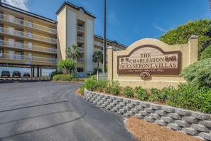 A sign for Charleston Oceanfront Villas with a multi-story building in the background.