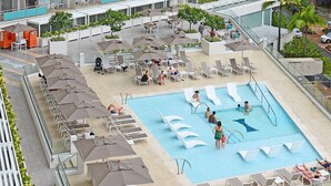 Ein Poolbereich auf dem Dach mit Liegestühlen, Sonnenschirmen und einem Schwimmbecken.