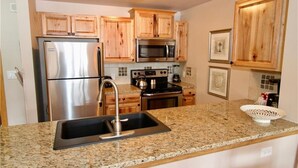 A kitchen with wooden cabinets, stainless steel appliances, granite countertops, and a sink.