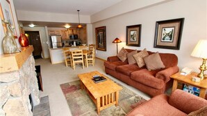 A living room with a sofa, coffee table, and a kitchen in the background.